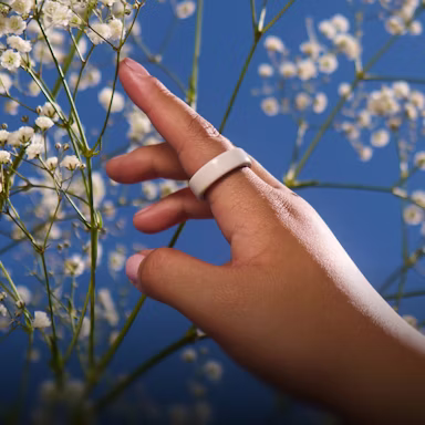 Close up of a person's hand with a Cloud Oura Ring 4 Ceramic on their finger