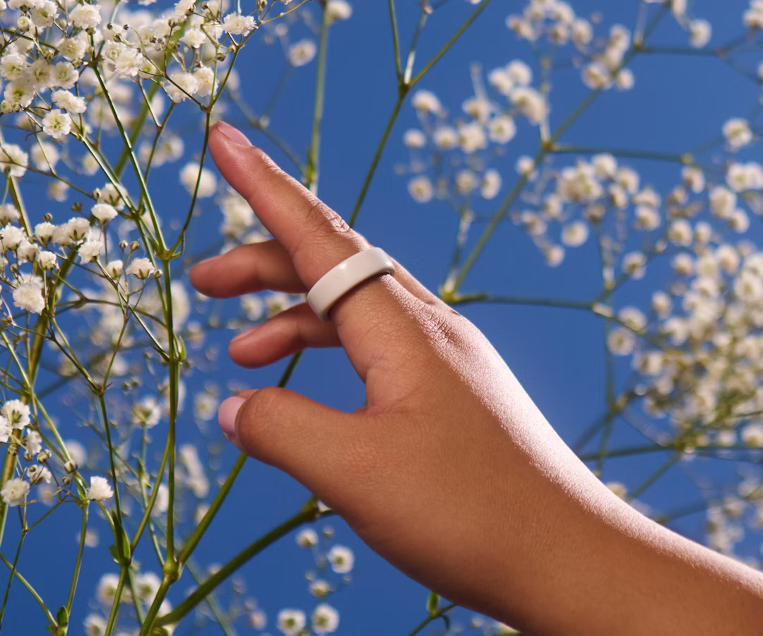 Close up of a person's hand with a Cloud Oura Ring 4 Ceramic on their finger